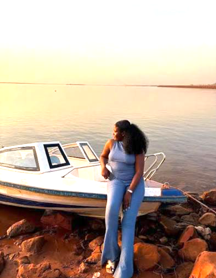 A person beside a boat at a waterside sunset