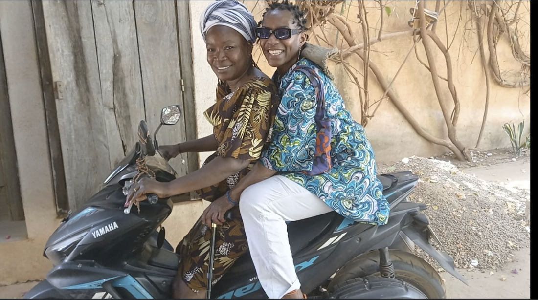Happy Afro-descendant visitor riding a motorbike during a warm community welcome in Burkina Faso